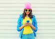 Fashion happy cool smiling girl using smartphone in colorful clo Fashion happy cool smiling girl using smartphone in colorful clo