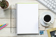 An empty page of a notebook in the center of a white wooden table at coffee time. Empty copy space for Editor's text. An empty page of a notebook in the center of a white wooden table at coffee time. Empty copy space for Editor's text.
