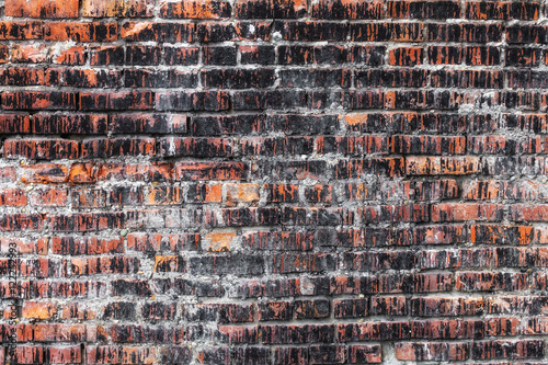 Weathered stained old dark brick wall, texture grunge background