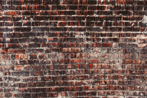 Weathered stained old dark brick wall, texture grunge background