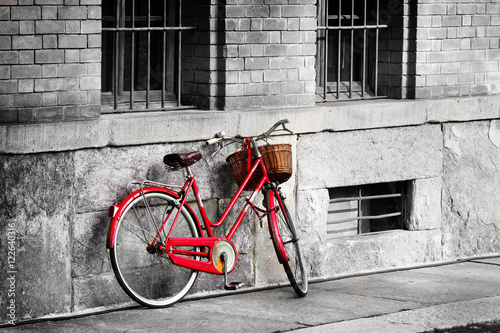  Bright red bicycle on the old street. Black and white filter applied.