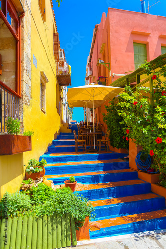Fototapeta na wymiar Cozy small Cretan cafe and colorful stairs between nice Cretan houses in Rethymnon, Island Crete, Greece