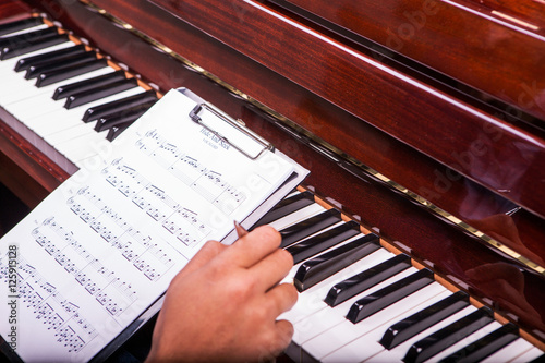 Fotoobraz na płótnie Trzymanie piosenki fortepianowej w schowku i granie na fortepianie z długopisem