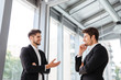 Two businessmen smiling and talking in office Two businessmen smiling and talking in office
