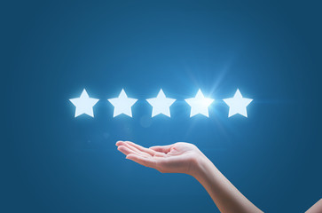 Businesswoman hand holding five stars isolated on blue background