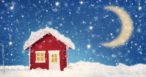Small red house model covered with snow in winter at night