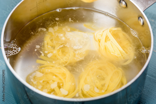 Fotoobraz na płótnie Dodawanie makaronu Tagliatelle w garnku z gorącą wodą do gotowania