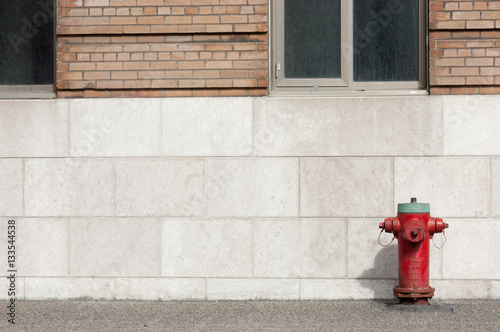Red and green fire hydrant below two windows on the street in Montreal, Quebec, Canada.  No people, room on the left for copy.
