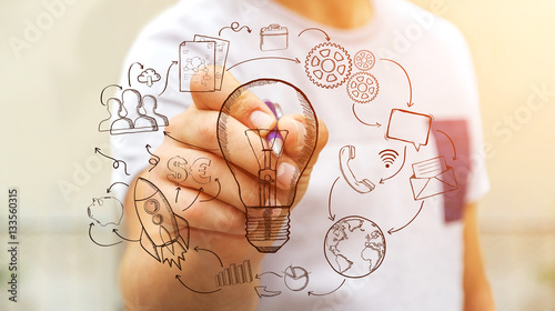 Businessman drawing a lightbulb with a pen with multimedia icons