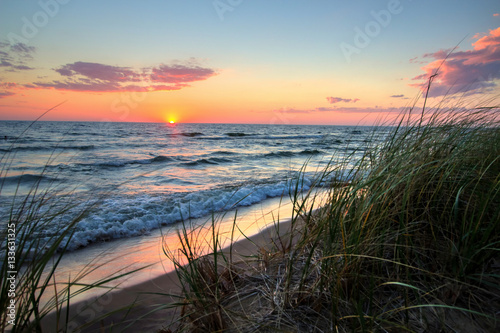 Plakat Spokojne Sunset Beach Tle. Piękny zachód słońca horyzont nad wodą z piaszczystej plaży i wydmy trawy na pierwszym planie. Park stanowy Hoffmaster. Muskegon, Michigan