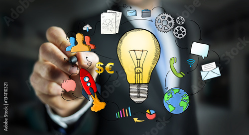 Businessman drawing a lightbulb with a pen with multimedia icons