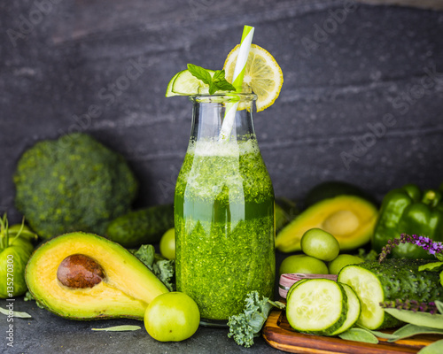 Plakat Zdrowy zielony smoothie w szklanej butelce na zmroku kamienia tle. Jedzenie wegetariańskie i dieta detoksykacyjna.