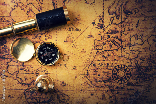 Fototapeta vintage compass and spyglass on old world map. copy space