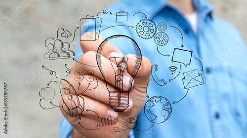 Businessman drawing a lightbulb with a pen with multimedia icons