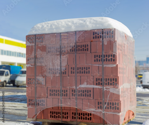 Pallet of the perforated red bricks on an outdoor warehouse