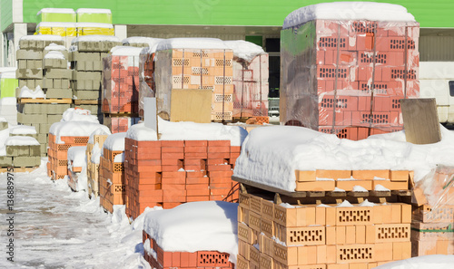 Pallets with red bricks and concrete masonry units on warehouse