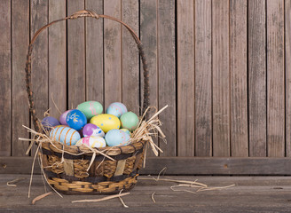 Easter Eggs in a Basket on a Weathered Wooden Surface and Background