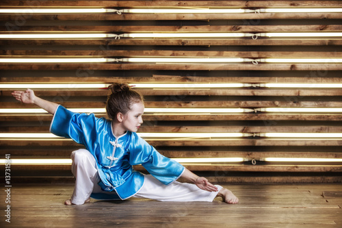 Fotoobraz na płótnie Całkiem mała dziewczynka w pokoju w sportowej odzieży dla sztuk walki to Wushu