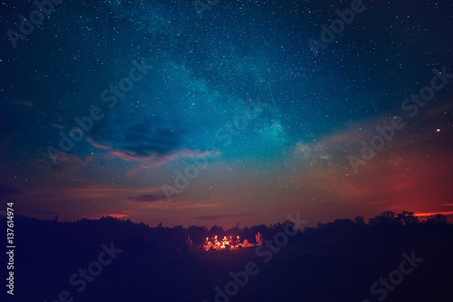 Plakat Camping ognia pod niesamowite niebieskie gwiaździste niebo z dużą ilością błyszczących gwiazd i chmur. Koncepcja rekreacyjnego wypoczynku na świeżym powietrzu.