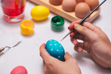 Happy Easter! Father painting Easter eggs on table.