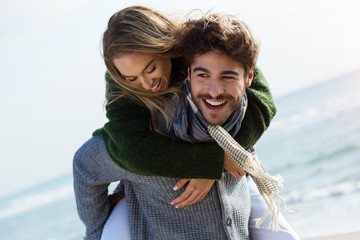 Happy young couple enjoying the day in a cold winter on the beach.