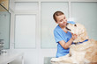 Young female veterinarian in blue uniform hugging and talking to white fluffy labrador lying on table during check-up Young female veterinarian in blue uniform hugging and talking to white fluffy labrador lying on table during check-up
