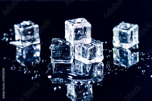 Fototapeta Iced cubes melting on a black table with reflection. Water. Melting of ice. 