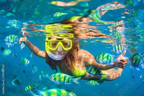 Zdjęcie XXL Szczęśliwa rodzina - dziewczyna w snorkeling maska nurkować pod wodą z ryby szkoły w basenie Morza rafy koralowej. Styl życia w podróży, przygoda na świeżym powietrzu w sportach wodnych, nauka pływania na letnich wakacjach na plaży z dzieckiem.