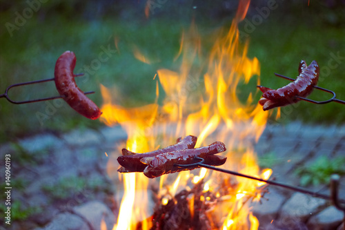 Zdjęcie XXL Grillowanie kiełbasek nad ogniskiem, obozowicze piecze kiełbaski na opiekanych widelcach