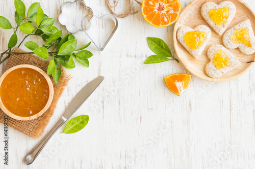 Orange jam with bread set on white rustic wooden table background