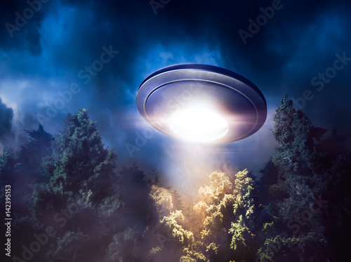 Fotoobraz na płótnie Wysoki kontrast obrazu UFO lecący nad lasem z wiązki światła w nocy