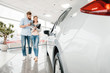 Happy couple holding catalog and choosing car in dealership salon Happy couple holding catalog and choosing car in dealership salon