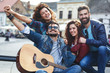Group of young people hangout on street in downtown.They standing by the city square,drinking and playing guitar. Group of young people hangout on street in downtown.They standing by the city square,drinking and playing guitar.