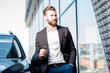 Happy buyer holding keys near the car in front of the modern avtosalon building Happy buyer holding keys near the car in front of the modern avtosalon building
