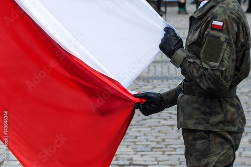 Fotoobraz na płótnie Polska flaga narodowa trzymana przez żołnierza podczas ceremonii