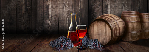 Fototapeta red wine glass bottle with barrel on vineyard wood