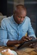 Man using digital tablet at wooden table in coffee house Man using digital tablet at wooden table in coffee house
