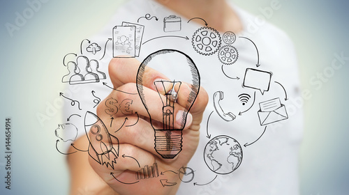 Businessman drawing a lightbulb with a pen with multimedia icons