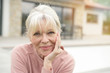 Portrait of blond senior woman sitting in front of new house Portrait of blond senior woman sitting in front of new house