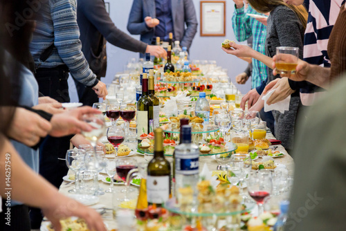 Fotoobraz na płótnie Pracownicy firmy na bankiecie. Stół z przysmakami, alkoholem i przekąskami. Uroczyste przyjęcie. Żywnościowy.