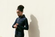 Young woman checking activity tracker on her wrist during outdoor exercise, standing at wall Young woman checking activity tracker on her wrist during outdoor exercise, standing at wall