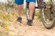 Piernas de un chico joven con una bicicleta de montaña en un camino rodeado de flores amarillas Piernas de un chico joven con una bicicleta de montaña en un camino rodeado de flores amarillas