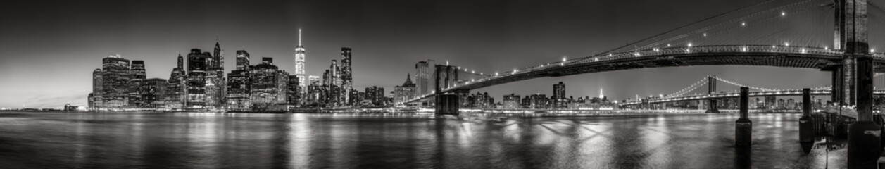 Panoramic Black and white view of Lower Manhattan Financial District skyscrapers at twilight with the Brooklyn Bridge and East River. New York City