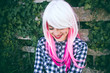 Chica adolescente alternativa con el pelo rosa y blanco, que lleva piercings, con un fondo de madera y hojas Chica adolescente alternativa con el pelo rosa y blanco, que lleva piercings, con un fondo de madera y hojas