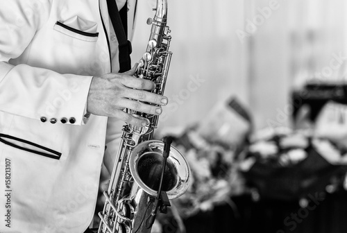 Fotoobraz na płótnie Saksofonista w białej kurtce gra na saksofonie. Saksofonisty jazzowy mężczyzna z saksofonem na przyjęciu weselnym