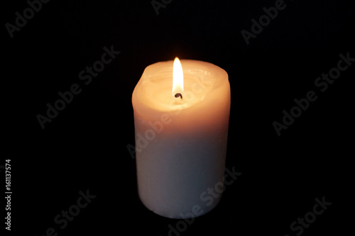 candle burning in darkness over black background