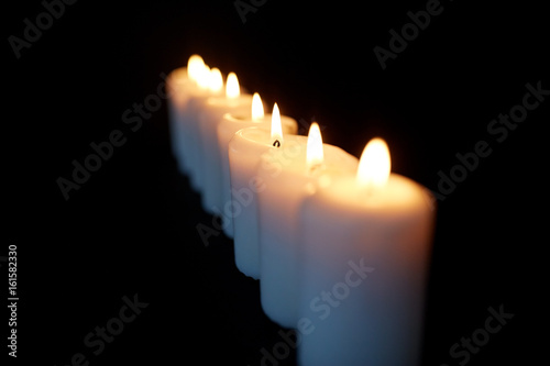 candles burning in darkness over black background
