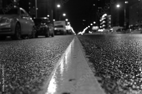 Zdjęcie XXL Nocne miasto. Asfalt w centrum uwagi jest widoczny w jego wyposażeniu technicznym. Asfalt po deszczu mokry