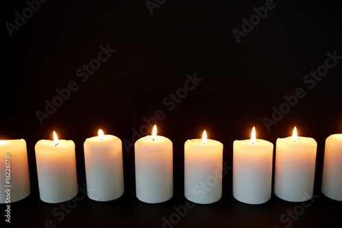 candles burning in darkness over black background