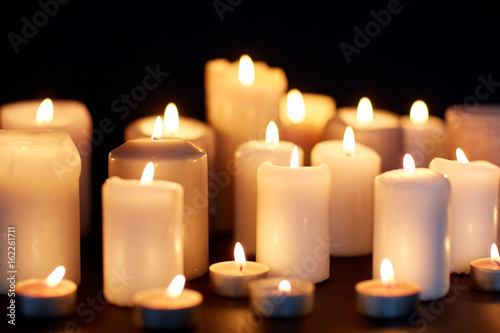 candles burning in darkness over black background